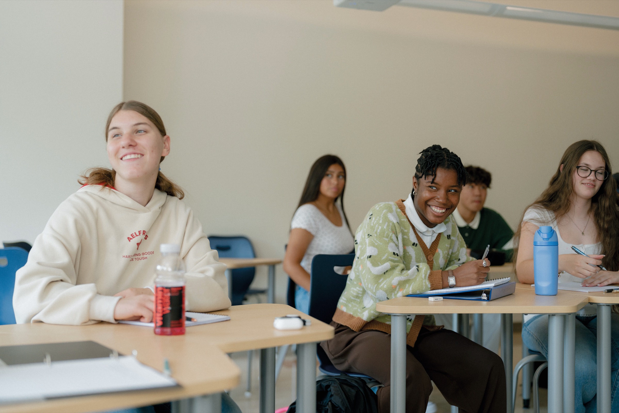 An upper school student smiling at her desk